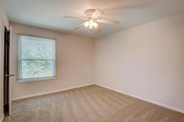 an empty room with a chandelier fan and window