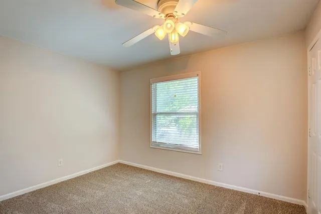 an empty room with a window and a fan