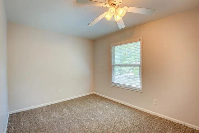 an empty room with a window and a fan