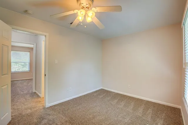 an empty room with a chandelier fan and windows