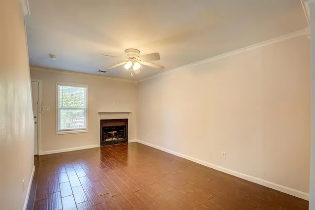 an empty room with wooden floor fireplace and windows