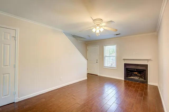 an empty room with wooden floor fireplace and windows