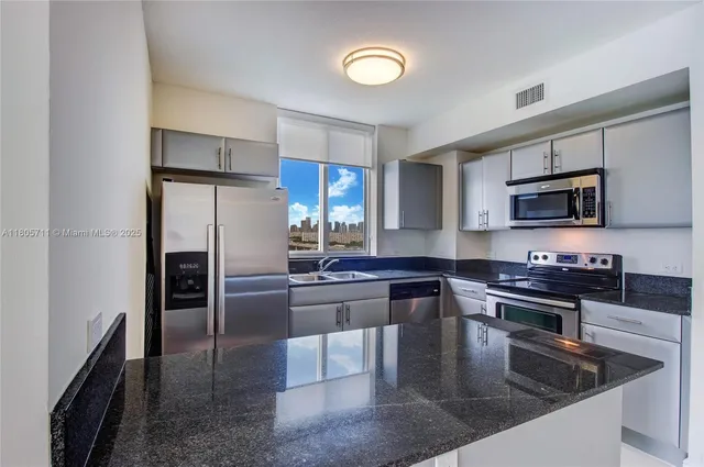 a kitchen with stainless steel appliances granite countertop a sink a stove top oven a refrigerator and dishwasher