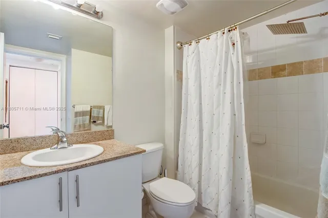 a bathroom with a sink toilet a mirror and shower curtain