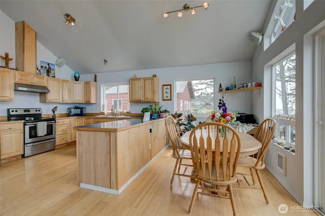 a kitchen with stainless steel appliances kitchen island granite countertop a stove top oven a sink a counter space and cabinets