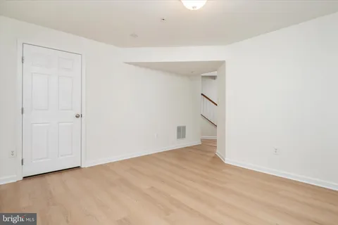 a view of an empty room with wooden floor and entryway