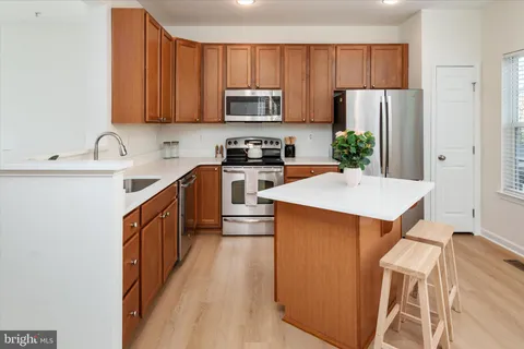 a kitchen with stainless steel appliances a stove a sink a refrigerator a center island and cabinets