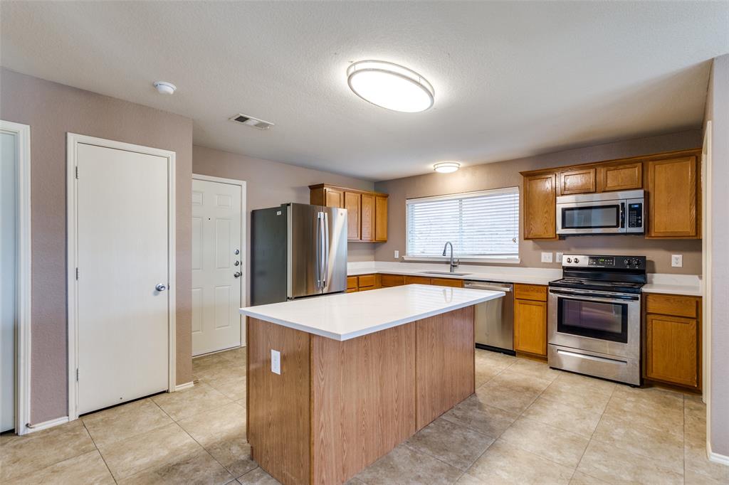 a room with stainless steel appliances kitchen island granite countertop a refrigerator and a stove top oven