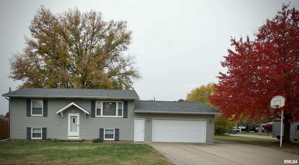 a front view of a house with a garden and tree