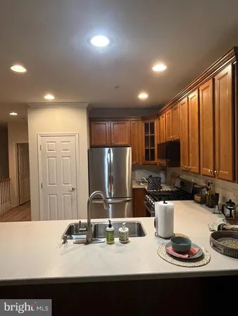 a kitchen with stainless steel appliances granite countertop a stove top oven a sink dishwasher and a refrigerator with wooden floor