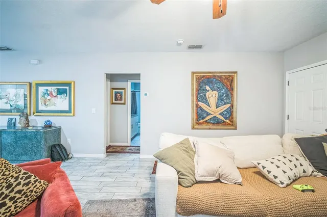 a living room with furniture a chandelier fan and a window