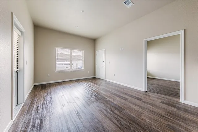 an empty room with wooden floor and windows