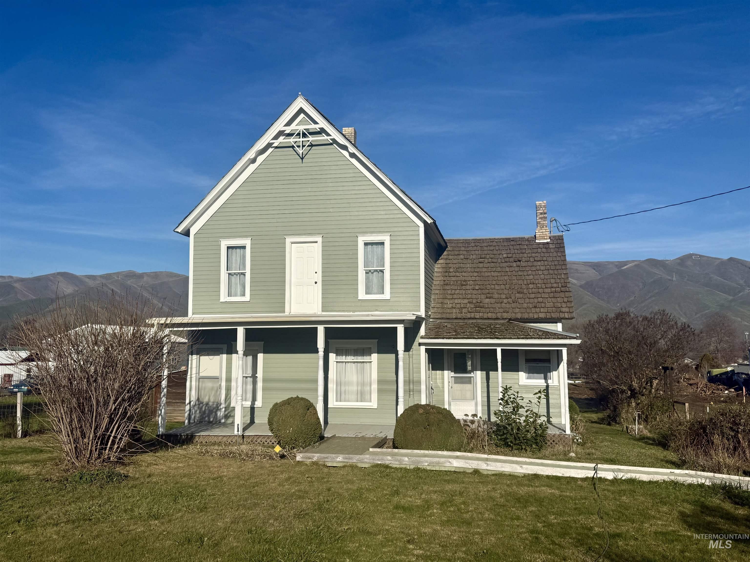 Back of property with a mountain view, a lawn, and a porch