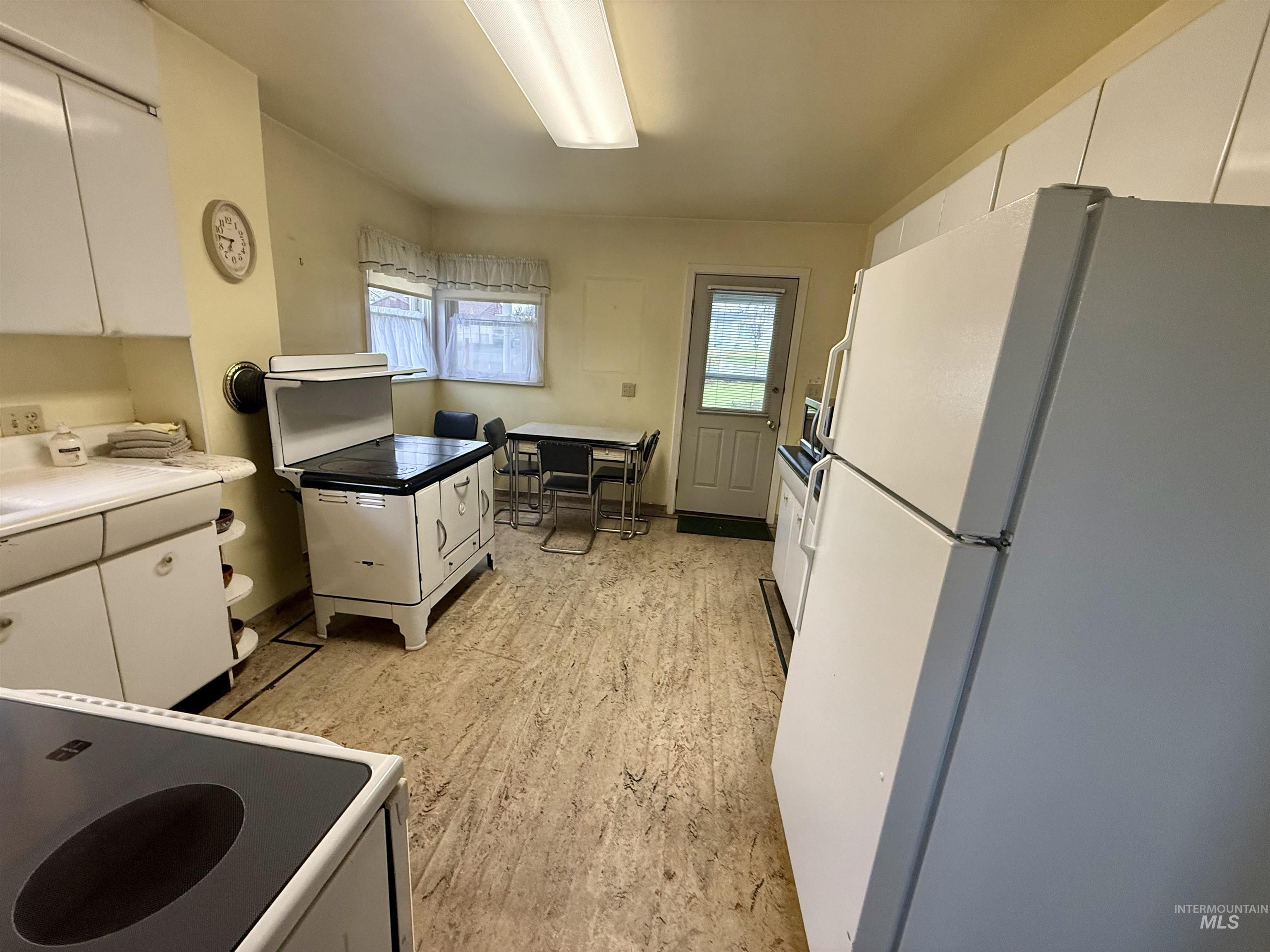 1368 Chestnut Street Clarkston, WA 99403 - Photo 4 of 25 Kitchen featuring white cabinetry, white appliances, light countertops, and light wood-style floors
