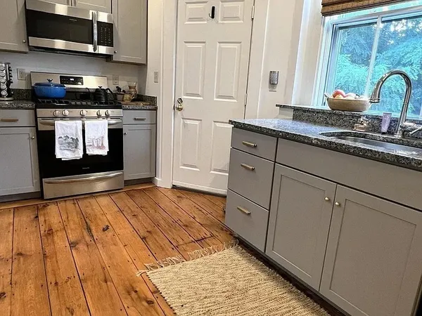 a kitchen with stainless steel appliances granite countertop a stove a sink and white cabinets