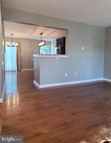 a view of a livingroom with wooden floor and kitchen space