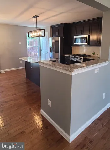 a kitchen with kitchen island granite countertop a stove and a wooden floor