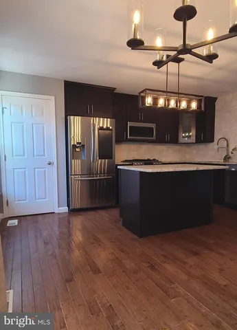 a kitchen with stainless steel appliances granite countertop a sink a stove and a wooden floors
