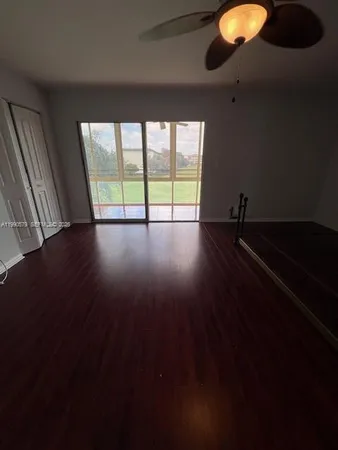 a view of an empty room with wooden floor and windows