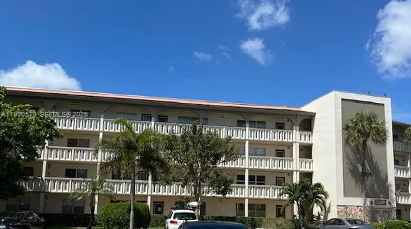 a front view of a building with glass windows and palm trees