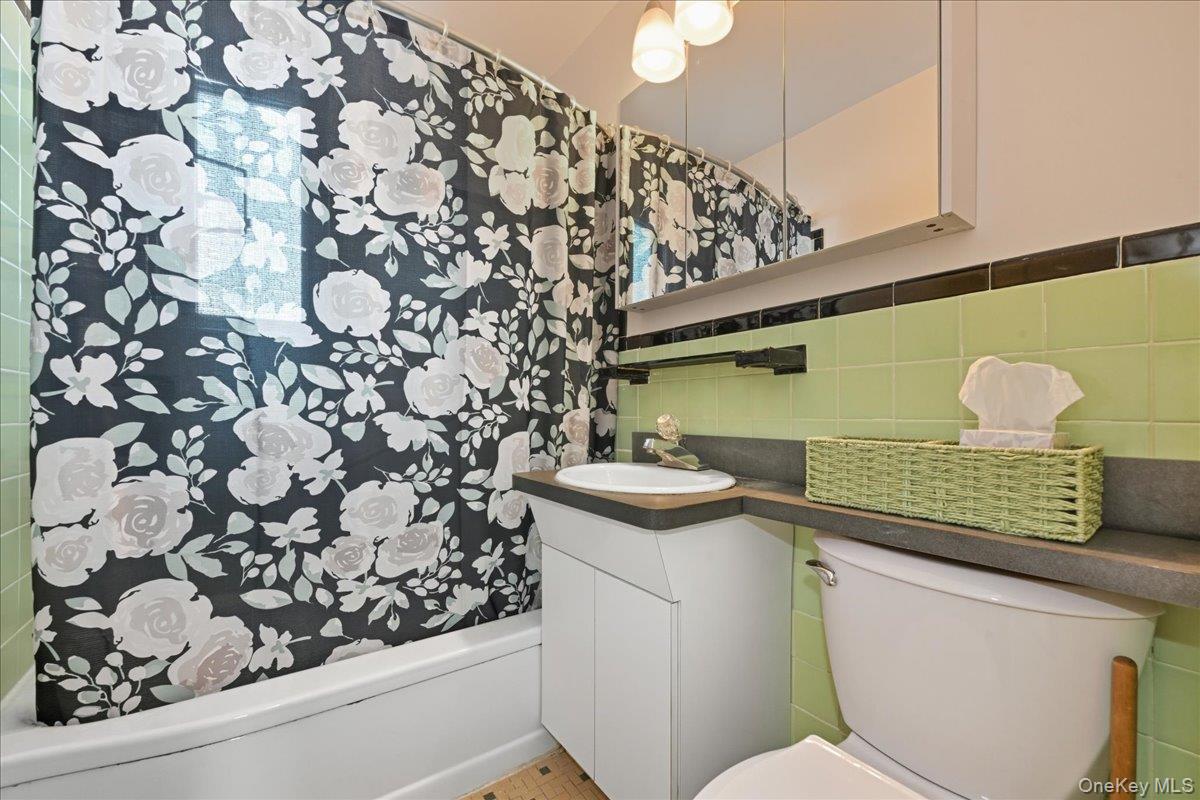218-03 68th Avenue, Unit 1 Queens, NY 11364 - Photo 13 of 13 Bathroom featuring vanity, tile walls, and shower / bathtub combination with curtain