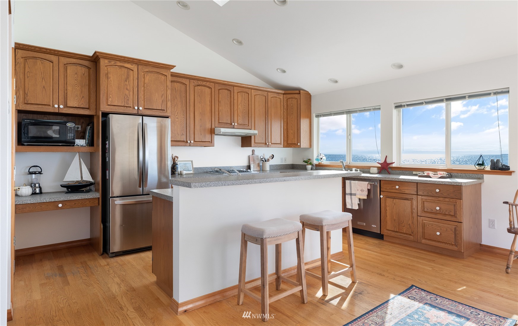 2585 West Beach Road Oak Harbor, WA 98277 - Photo 14 of 38 a kitchen with stainless steel appliances granite countertop a refrigerator a stove a sink dishwasher and white cabinets with wooden floor