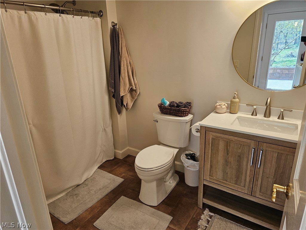 2363 Tabor Ridge Road Northeast New Philadelphia, OH 44663 - Photo 38 of 42 Bathroom featuring a single vanity with wood-finish cabinetry and a white countertop, coordinating round mirror, and a full shower with a curved shower rod