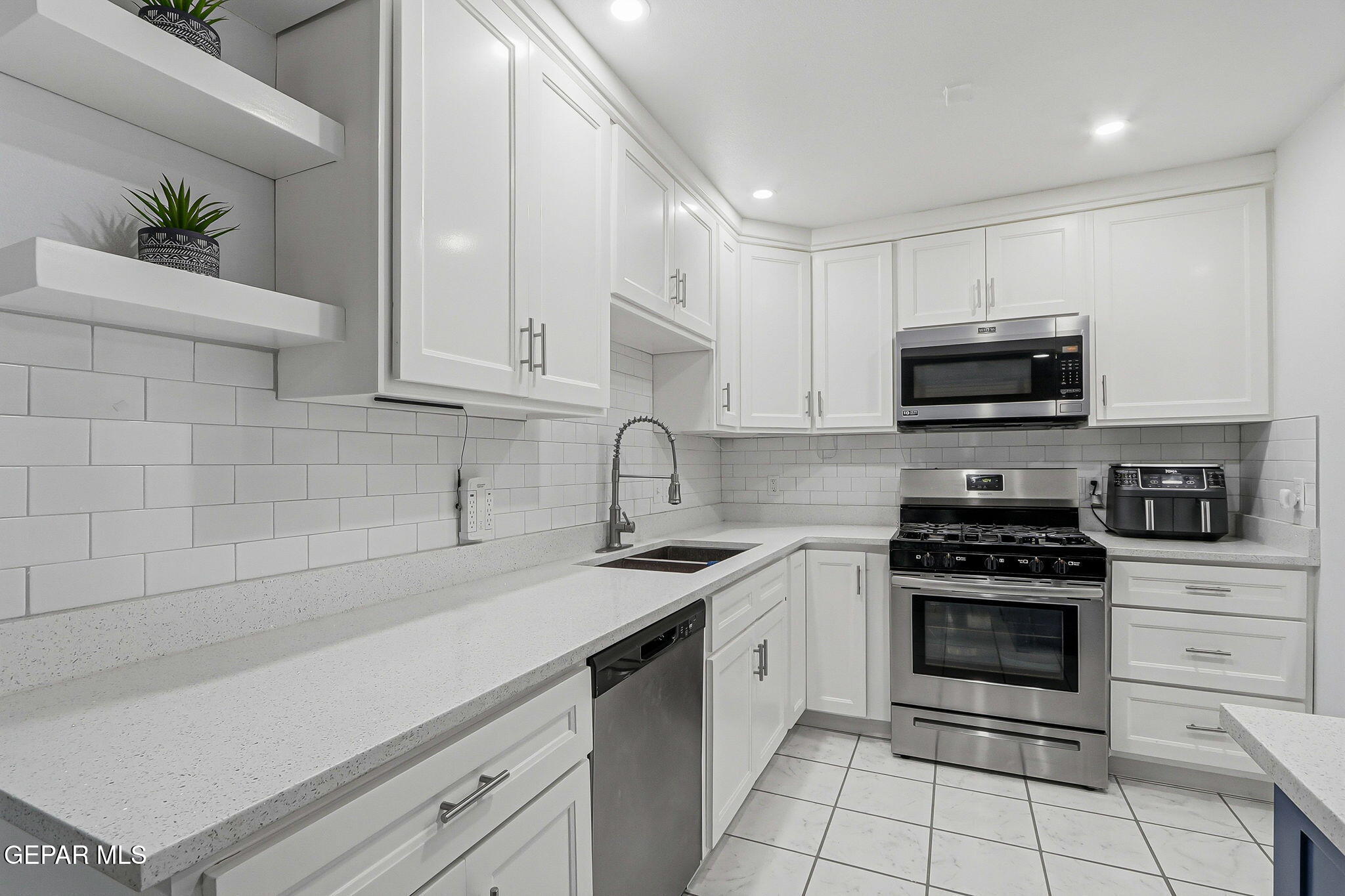 10540 Socorro Road Socorro, TX 79927 - Photo 5 of 45 a kitchen with granite countertop a stove a sink and a microwave