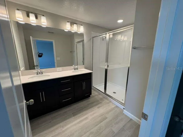 a spacious bathroom with a double vanity sink a toilet and a mirror
