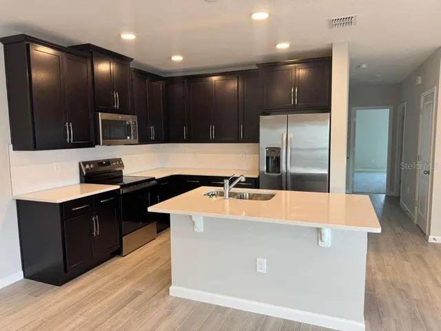 a large kitchen with stainless steel appliances kitchen island a large counter top and a wooden floors