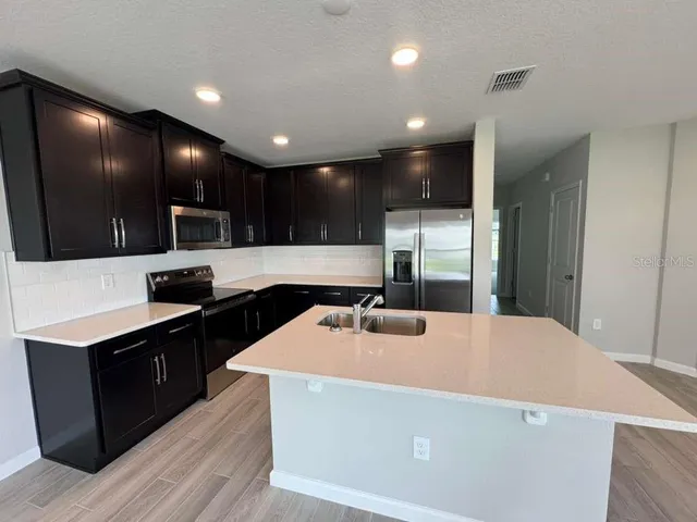 a kitchen with kitchen island a sink stainless steel appliances and cabinets