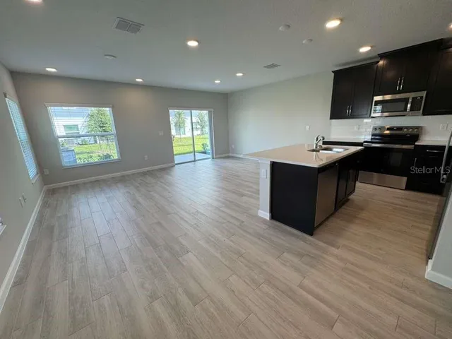 a view of kitchen with kitchen island wooden floors granite counter tops and white appliances
