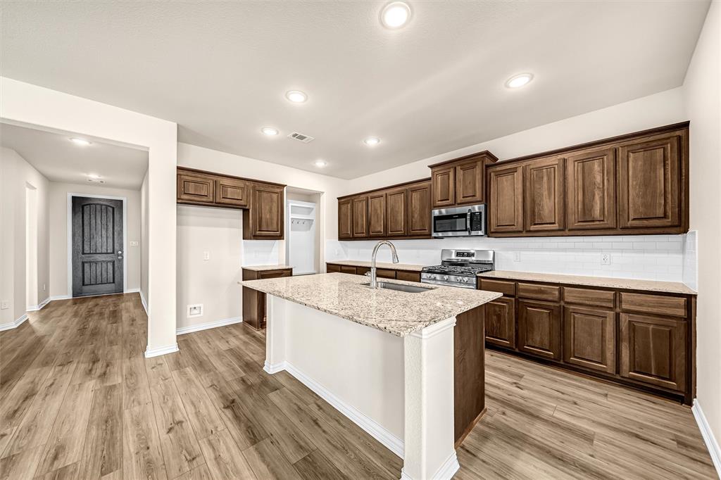 3516 Columbus Street Gainesville, TX 76240 - Photo 13 of 40 a kitchen with stainless steel appliances granite countertop wooden cabinets a refrigerator a stove a sink and dishwasher with wooden floor