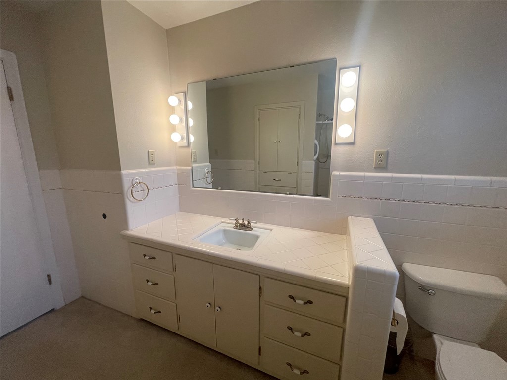 1008 North Bosque Street Meridian, TX 76665 - Photo 2 of 36 a bathroom with a toilet sink and mirror