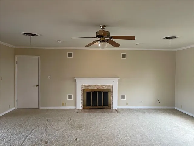 an empty room with a chandelier fan and windows