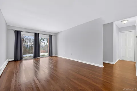 a view of an empty room with glass door and wooden floor
