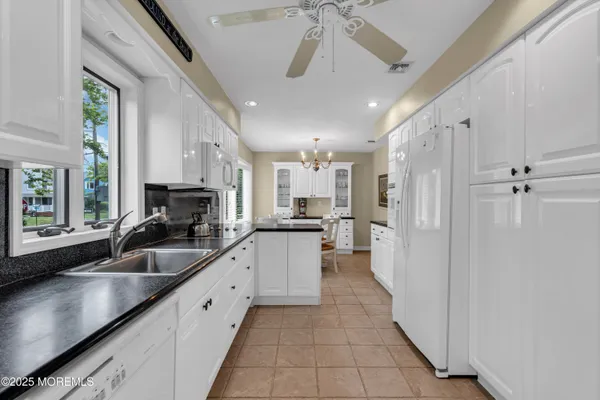 a kitchen with stainless steel appliances a sink a refrigerator a counter top space cabinets and a chandelier