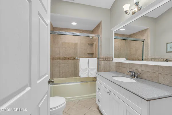 a bathroom with a granite countertop sink a mirror a toilet and bathtub