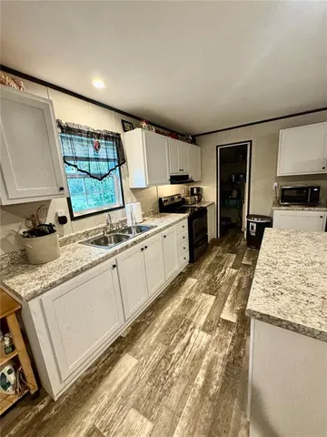 a large kitchen with granite countertop a sink and a stove top oven