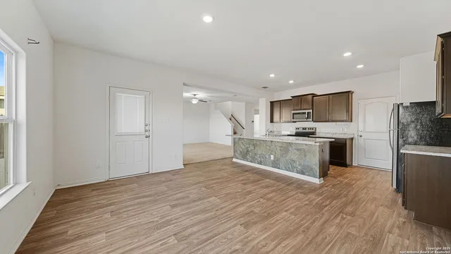 a large kitchen with a center island wooden floor stainless steel appliances and a window