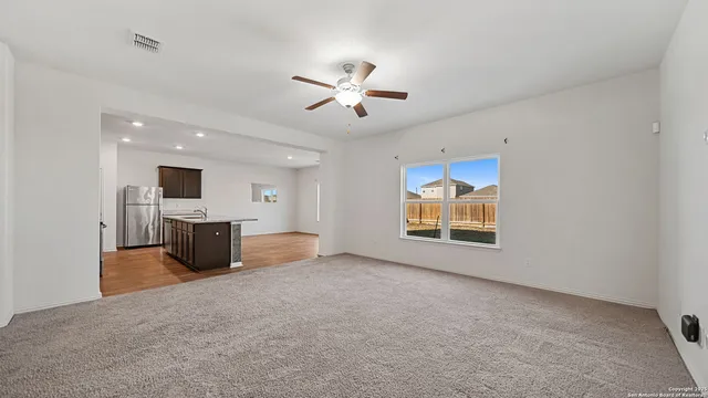 an empty room with windows and a ceiling fan
