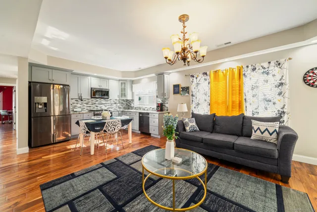 a living room with furniture kitchen view and a chandelier