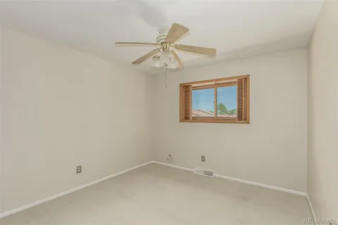 an empty room with a window and a fan