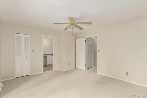 an empty room with closet and a ceiling fan