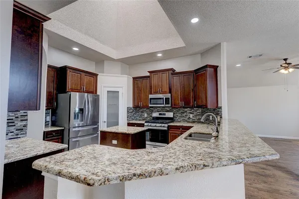 a kitchen with kitchen island granite countertop a sink stove and refrigerator