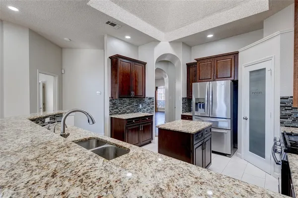 a kitchen with granite countertop kitchen island stainless steel appliances a sink stove and refrigerator
