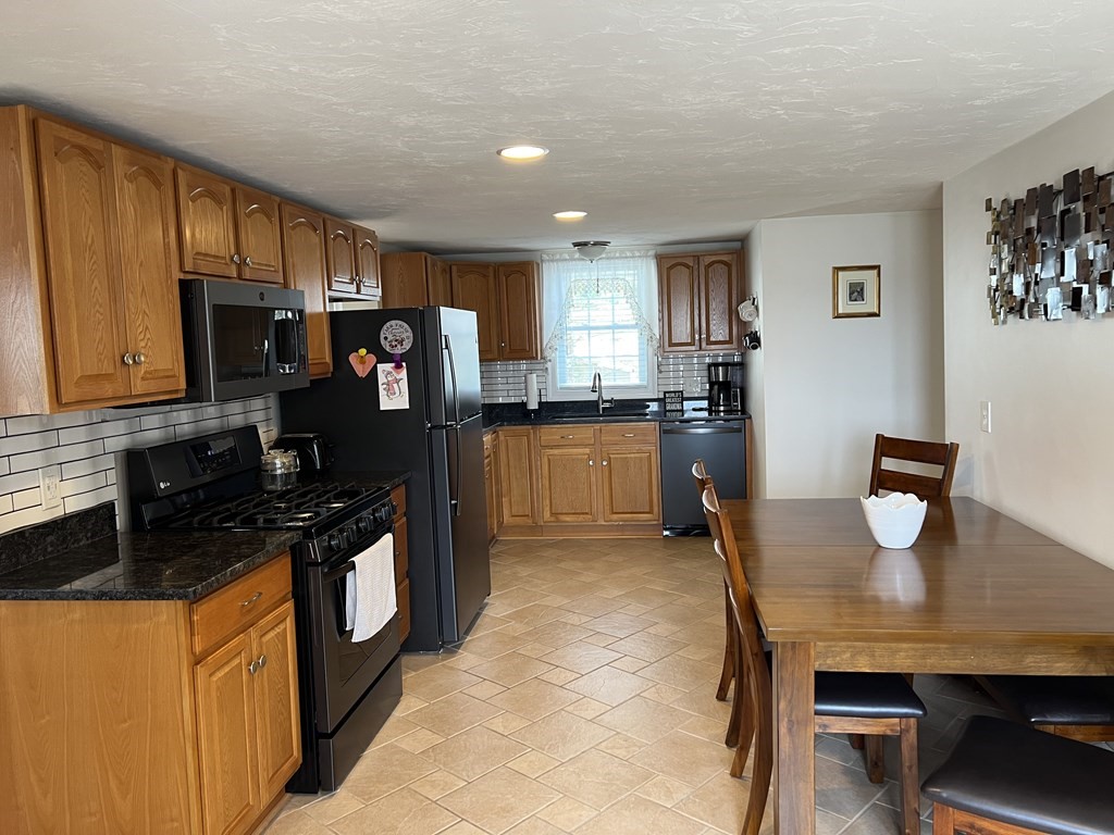 34 Colonial Road Webster, MA 01570 - Photo 3 of 35 a kitchen with stainless steel appliances granite countertop a stove top oven a sink dishwasher a dining table and chairs with wooden floor