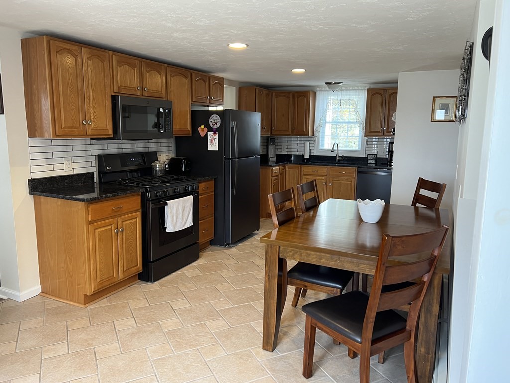 34 Colonial Road Webster, MA 01570 - Photo 5 of 35 a kitchen with granite countertop a table chairs microwave and refrigerator