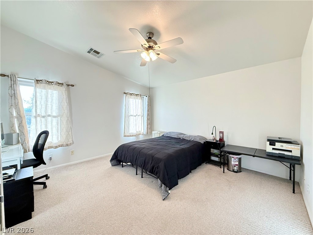 1220 East Gamebird Road Pahrump, NV 89048 - Photo 12 of 49 A well-lit bedroom features vaulted ceilings and plush carpeting throughout.