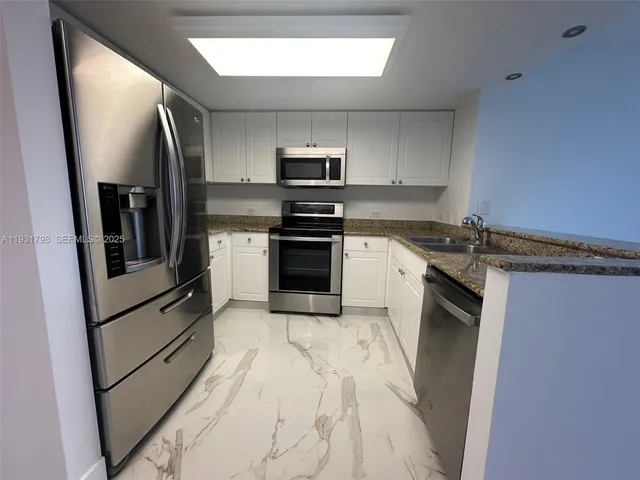 a kitchen with stainless steel appliances granite countertop a stove a refrigerator and a sink